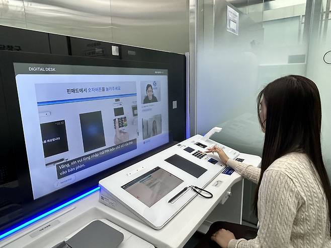 베트남인 부튀링 씨가 지난 23일 서울 중구 서소문에 있는 신한은행 인공지능(AI) 브랜치에서 디지털 데스크를 통해 실시간 AI 통번역 서비스를 바탕으로 체크카드를 발급받고 있다. [김은희 기자]
