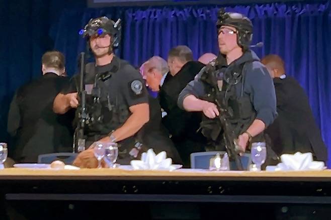 트럼프 대통령(왼쪽 셋째)이 전날 워싱턴 힐튼호텔에서 열린 백악관 기자단과의 연례 만찬 행사 도중 총성이 들리자 비밀경호국 요원들의 경호를 받으며 행사장을 빠져나가고 있다. 용의자는 현장에서 체포됐다. 로이터=연합뉴스