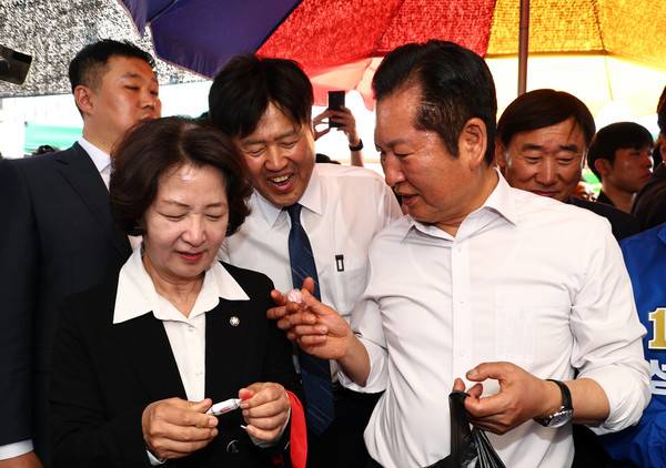 더불어민주당 정청래 대표가 19일 경기도 성남시 모란민속5일장을 방문해&nbsp;김용&nbsp;전 민주연구원 부원장(가운데)에게 사탕을 건네고 있다. 김용&nbsp;전 민주연구원 부원장은 28일 6·3 지방선거와 함께 치러지는 국회의원 재·보궐선거 공천에서 배제되자 "백의종군하겠다"는 입장을 밝혔다. 2026.4.19. [사진=연합뉴스]