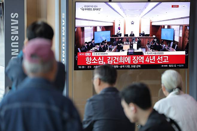 28일 서울역 대합실에서 시민들이 통일교 금품 수수와 도이치모터스 주가조작, 명태균 무상 여론조사 등의 혐의를 받는 김건희 여사 항소심 선고공판 생중계를 시청하고 있다. [사진=연합뉴스]