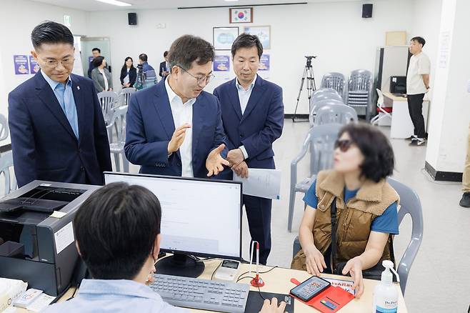 김동연 경기지사(가운데)가 27일 안양시 동안구 관양동 행정복지센터를 방문해 고유가 피해지원금을 신청한 도민과 대화하고 있다. 경기도 제공