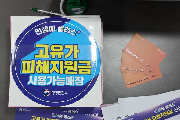 고유가&nbsp;피해지원금 사용가능매장을 알리는 스티커와 사용 카드가 놓여 있다. 연합뉴스