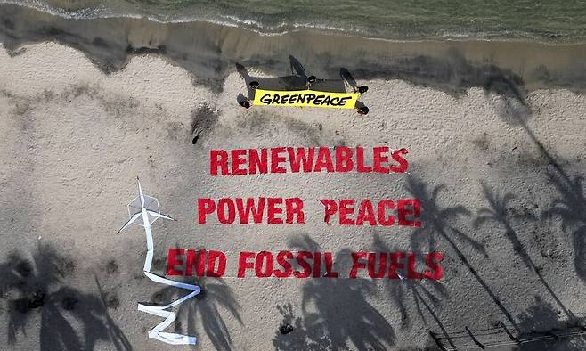 지난 27일(현지시각) 콜롬비아 산타마르타에서 열린 제1차 화석연료로부터의 전환 국제회의 중 그린피스 회원들이 ‘재생에너지 평화, 화석연료 끝내자’란 구호를 회의장 인근 포트해변에 쓴 모습. AFP/연합뉴스