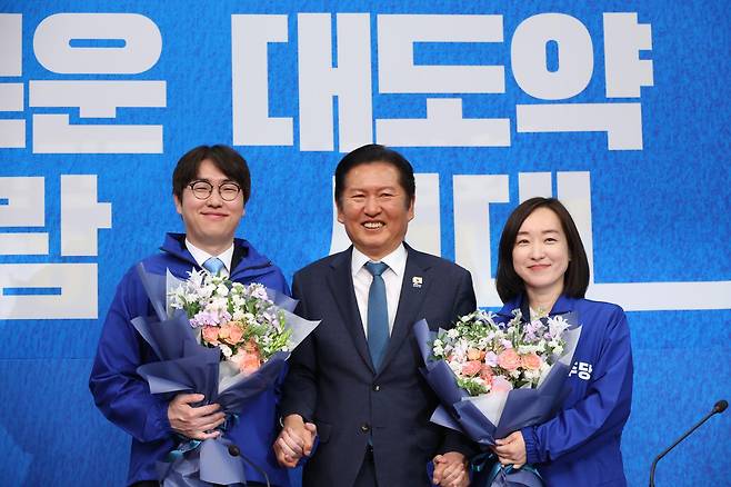6·3 재보선에 격전지로 떠오른 부산 북구갑 지역구에 출마할 것으로 예상되는 하정우(왼쪽) 전 청와대 AI수석과 아산을에 출마할 것으로 보이는 전은수(오른쪽) 전 청와대 대변인이 29일 국회에서 열린 더불어민주당 인재 영입식에서 꽃다발을 들고 정청래 당대표와 기념촬영하고 있다. 연합뉴스