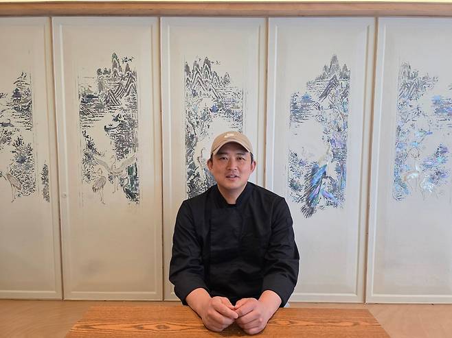 ‘맛에들면’의 트레이트마크와 같은 자개장 벽 앞에서 포즈를 취한 강성훈 사장       사진제공 ｜ 맛에들면