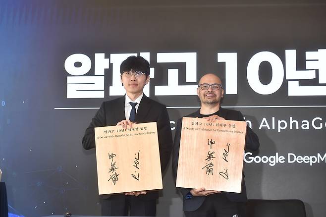 신진서 9단(왼쪽)이 29일 서울 중구 웨스틴조선호텔에서 열린 ‘알파고 10년 : 위대한 동행’ 행사에서 데미스 허사비스 구글 딥마인드 CEO와 기념대국을 한 뒤 사인을 한 바둑판을 들고 기념촬영을 하고 있다. 한국기원 제공