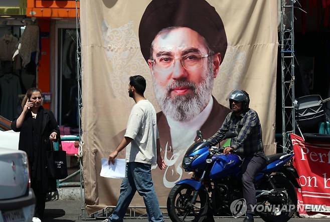 테헤란에 걸린 모즈타바 하메네이 사진 (테헤란 EPA=연합뉴스) 20206년 4월 28일 이란 수도 테헤란에 걸린 이란 최고지도자 아야톨라 모즈타바 하메네이의 사진이 인쇄된 포스터 앞을 시민들이 지나가고 있다. (EPA/ABEDIN TAHERKENAREH) 2026.4.29.