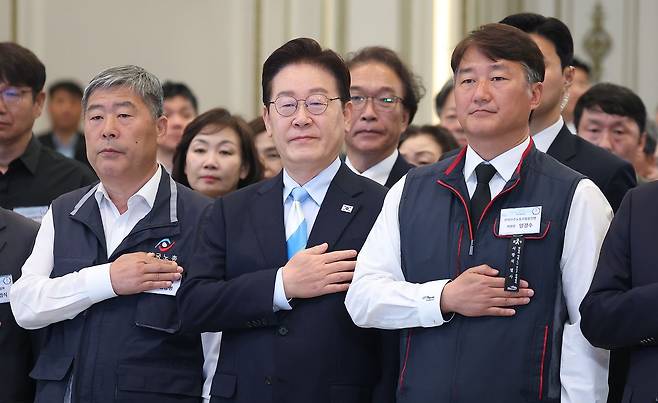 이재명 대통령이 1일 청와대 영빈관에서 열린 노동절 기념식에서 양대 노총 위원장을 비롯한 참석자들과 국민의례를 하고 있다.   청와대가 노동절 기념식을 개최한 것은 사상 처음이며, 양대 노총이 노동절 행사를 함께하는 것도 이번이 처음이다.   왼쪽부터 김동명 한국노총 위원장, 이 대통령, 양경수 민주노총 위원장. 연합뉴스