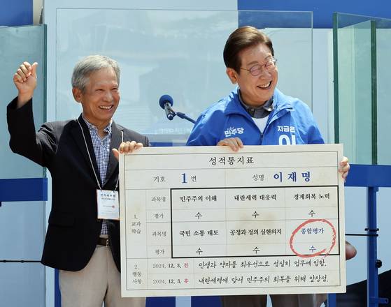 지난해 6월 1일 이재명 당시 더불어민주당 대선 후보가 경북 안동시 웅부공원에서 유세하기 전 삼계초등학교 6학년 담임이었던 은사 박병기(당시 73)씨로부터 성적표 패널을 받고 있다. 김성룡 기자