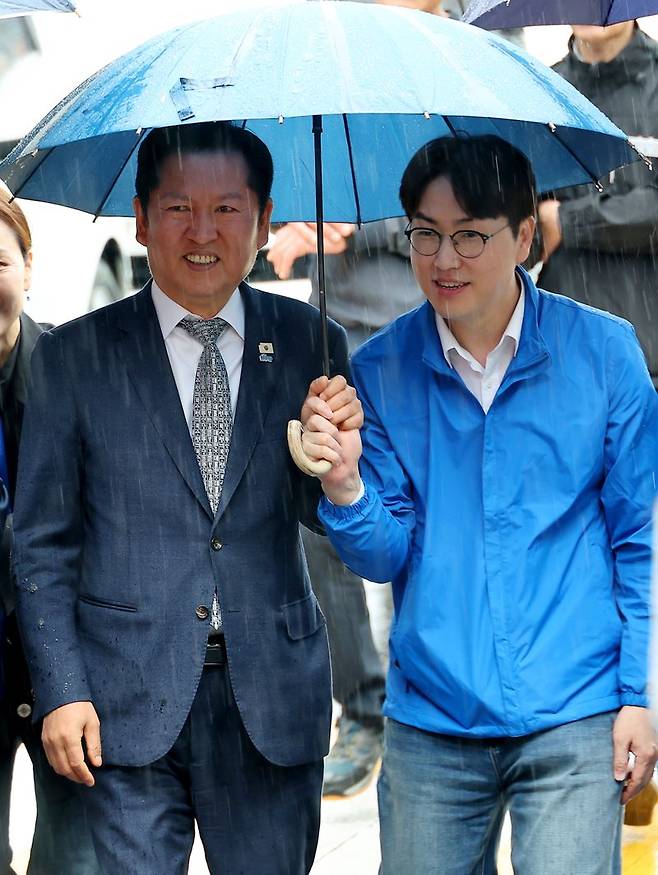 3일 오후 부산 북구 구포시장에서 더불어민주당 정청래 대표와 북갑 국회의원 보궐선거 출마를 공식화한 하정우 전 청와대 AI 미래기획수석이 우산을 쓰고 이동하고 있다. 연합뉴스