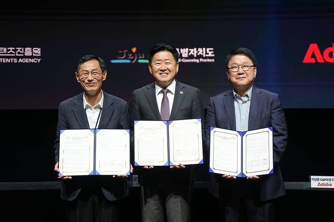 제주콘텐츠진흥원 강민부 원장(왼쪽부터), 오영훈 제주도지사, 이성순 어도비코리아 전무가 지난 3월 17일 제주 비인공연장에서 '생성형 인공지능(AI) 기반 콘텐츠 산업 활성화'를 위한 업무협약을 체결한 뒤 협약서를 들어 보이고 있다. 이번 협약은 생성형 AI 콘텐츠 인재 양성과 지역 콘텐츠 기업의 AI 기술 활용 지원, 글로벌 네트워크 연계 협력을 담고 있다. 제주특별자치도 제공