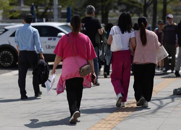 지난 4월 13일 서울 광화문광장 인근에서 외국인과 시민들이 겉옷을 들거나 허리에 묶은 채 이동하고 있다. [사진=연합뉴스]