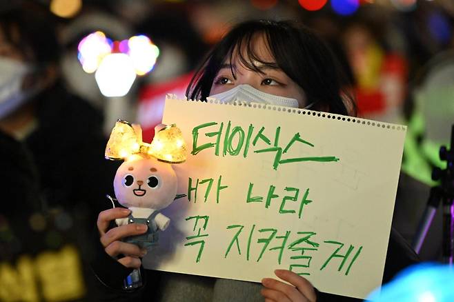 한 시민이 2024년 12월 11일 국회 앞에서 열린 윤석열 대통령 탄핵 촉구 촛불집회에서 한 아이돌 그룹의 응원봉을 들고 탄핵을 촉구하고 있다. 박시몬 기자