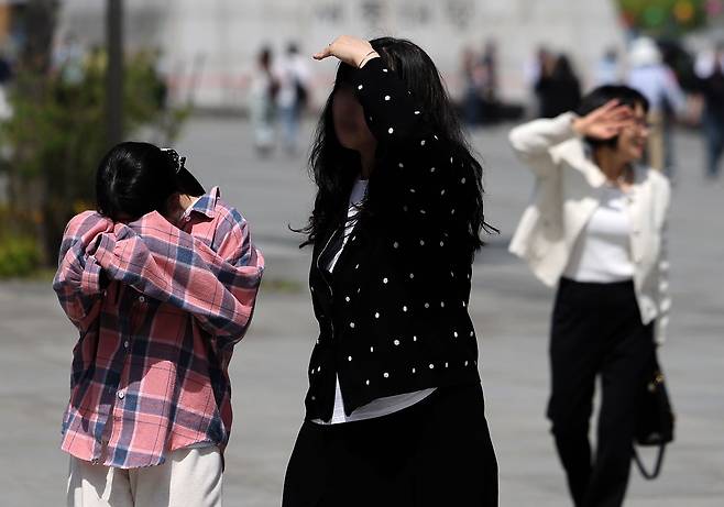 지난달 19일 서울 종로구 광화문광장에서 시민들이 손으로 햇볕을 가리며 길을 걷고 있다. 뉴시스