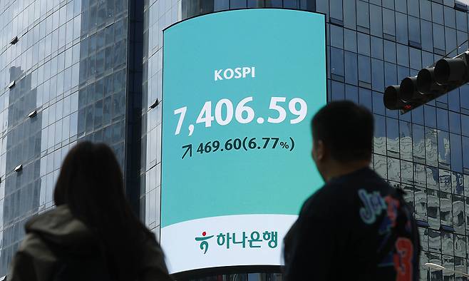 장중 7400 터치 코스피가 사상 처음으로 7000고지를 밟은 6일 시민들이 서울 중구 하나은행 외벽 전광판에 표시된 코스피 지수를 바라보고 있다. 유희태 기자
