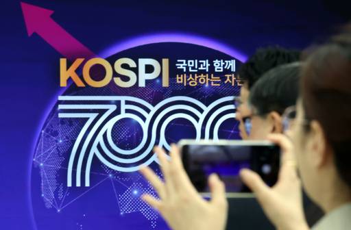 사상 처음으로 코스피 7000p를 돌파한 지난 6일 부산 남구 부산국제금융센터 내 한국거래소 홍보관에서 열린 축하행사에 참석한 한 관계자가 휴대전화로 촬영하고 있다. /뉴시스