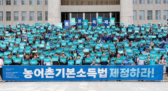 지난해 9월 12일 서울 여의도 국회에서 열린 '농어촌기본소득 입법 촉구 500인 기자회견'에서 참가자들이 구호를 외치고 있다. 뉴스1