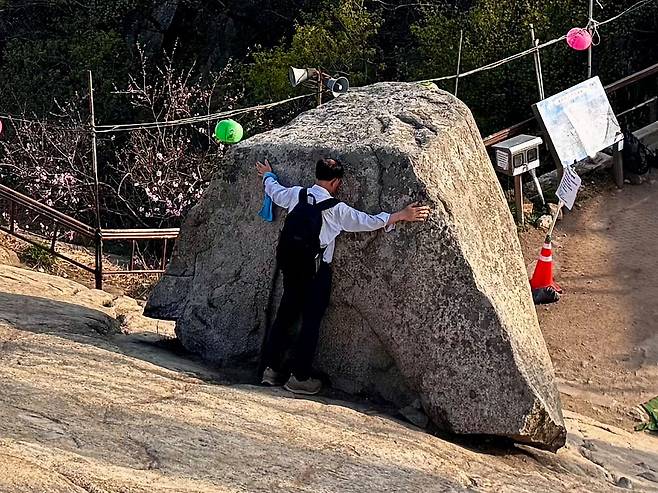 관악산 정상의 너른 바위 차일암에서 한 남성이 기운을 받으려는 듯 정상석을 껴안고 있다. 김홍준 기자