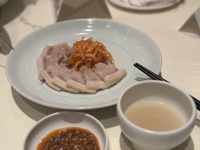 Boiled pork slices, spicy radish salad and ssamjang paired with Yun Judang Takju 12 (Tammy Park/The Korea Herald)