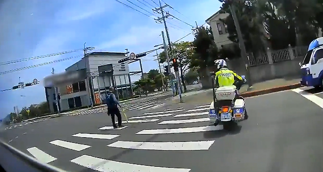 지난달 25일 제주시 연삼로 인근 교차로 횡단보도에서 경찰이 고령 보행자의 횡단을 돕는 모습 (제주경찰청 제공)