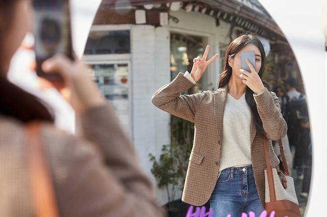 A woman takes a selfie in front of a mirror while making a V sign with her hand. (Getty Images Bank)