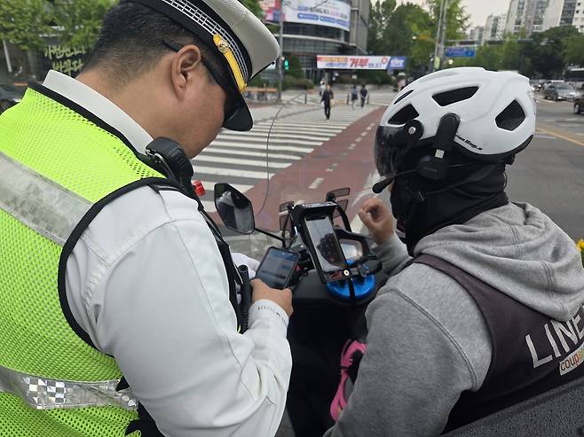 지난 12일 오후 2시 50분께 서울 강남구 대치역 사거리에서 경찰이 보행자보호의무를 위반한 배달 기사에게 범칙금을 부과하고 있다. 이영기 기자.