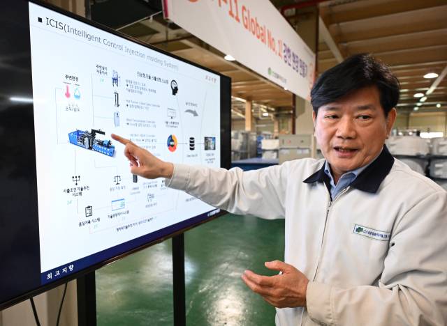 이동한 신성델타테크 대표이사가 공장 현장에서 ICIS(Intelligent Control Injection molding System·지능형 자율 사출성형 시스템) 구성도를 가리키며 설명하고 있다.