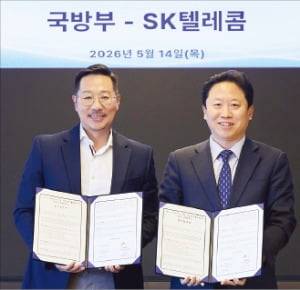 14일﻿ SKT타워에서 열린 ‘독자 AI 파운데이션 모델 국방 분야 활용’ 업무협약(MOU)﻿에서 김명국 SK텔레콤 본부장(왼쪽)과 전준범 국방부 국방인공지능기획국장이 ﻿사진을 촬영하고 있다.  /SK텔레콤 제공