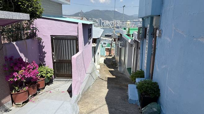 A view framed by pastel-toned homes in Bongsan Village, Bongnae-dong, Yeongdo District, shows the water and mountains on May 5. [WOO JI-WON]