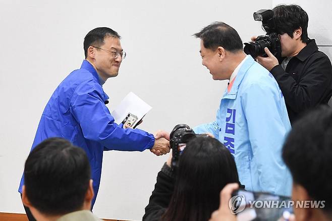 악수하는 김상욱과 김종훈 (울산=연합뉴스) 25일 울산시의회 프레스센터에서 더불어민주당 김상욱 의원(왼쪽)과 진보당 김종훈 전 동구청장이 우연히 만나 악수하고 있다. 6ㆍ3 지방선거에서 울산시장 후보로 출마하는 이들은 범진보 진영 후보 단일화 작업을 진행할 것으로 예상된다. 2026.3.25 [울산시의회 제공. 재판매 및 DB 금지] hkm@yna.co.kr