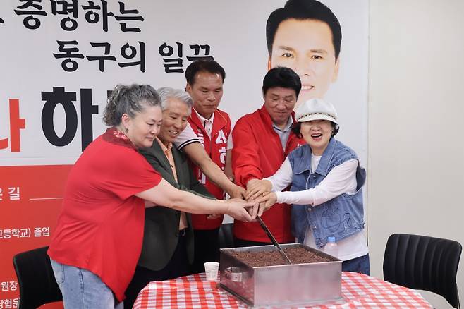 하중호 국민의힘 대구 동구의원 후보와 강대식 국회의원, 지지자들이 당선을 기원하며 떡을 자르고 있다. 하중호 후보 제공