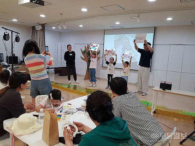 태극기와 ‘자유보장’ 글씨에 색과 그림을 입힌 가족들이 완성한 작품을 들어보이고 있다.