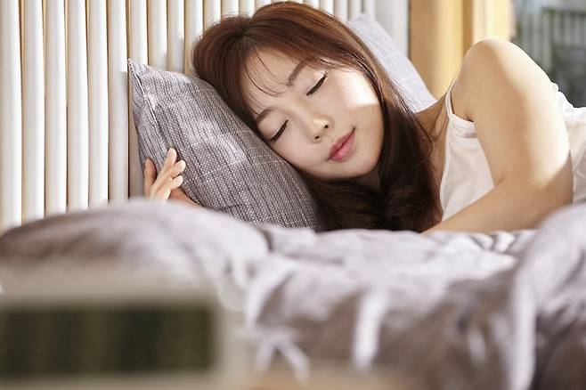 아늑한 침실에서 베개를 끌어안고 편안하게 잠든 모습. 깊은 수면과 휴식을 표현한 수면 건강 이미지. 게티이미지뱅크