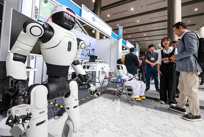 지난 4월 서울 강남구 코엑스 그랜드볼룸에서 열린 '2026 자율제조AI 월드쇼'를 찾은 관람객들이 휴머노이드 산업 로봇을 살펴보고 있다./뉴스1