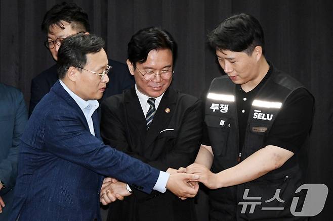 20일 경기도 수원시 장안구 경기고용노동청에서 열린 삼성전자 임금협상을 마친 후 여명구 삼성전자 DS(디바이스솔루션·반도체 사업 담당) 피플팀장과 김영훈 고용노동부 장관, 최승호 삼성그룹 초기업노동조합 삼성전자지부 위원장이 잠정 합의한에 서명한 후 손을 맞잡고 있다. (공동취재) 2026.5.20 ⓒ 뉴스1 김영운 기자