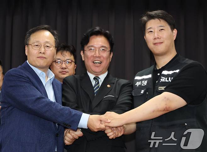 20일 경기 수원시 장안구 경기고용노동청에서 열린 삼성전자 임금협상을 마친 후 여명구 삼성전자 DS(디바이스솔루션·반도체 사업 담당) 피플팀장(왼쪽부터)과 김영훈 고용노동부 장관, 최승호 삼성그룹 초기업노동조합 삼성전자지부 위원장이 잠정 합의한에 서명한 후 손을 맞잡고 있다. 2026.5.20 ⓒ 뉴스1 김영운 기자