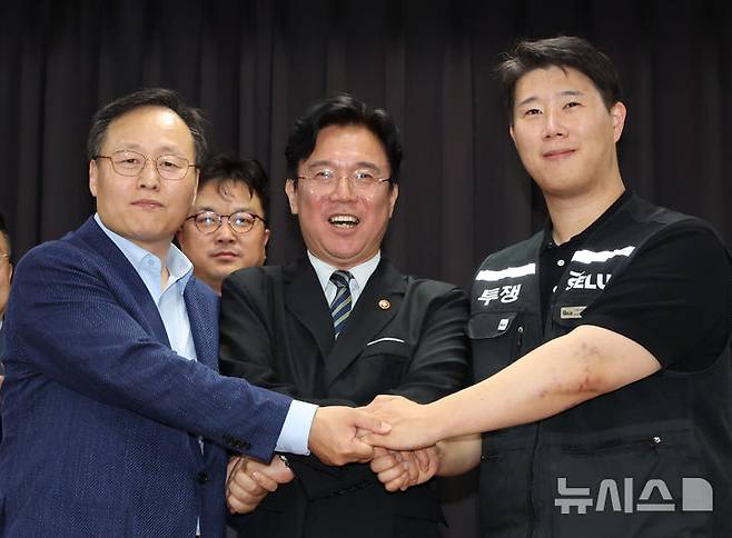 20일 경기 수원시 장안구 경기고용노동청에서 열린 삼성전자 임금협상을 마친 후 여명구 삼성전자 DS(디바이스솔루션·반도체 사업 담당) 피플팀장(왼쪽부터)과 김영훈 고용노동부 장관, 최승호 삼성그룹 초기업노동조합 삼성전자지부 위원장이 잠정 합의한에 서명한 후 손을 맞잡고 파이팅을 외치고 있다. /제공=뉴시스(공동취재)