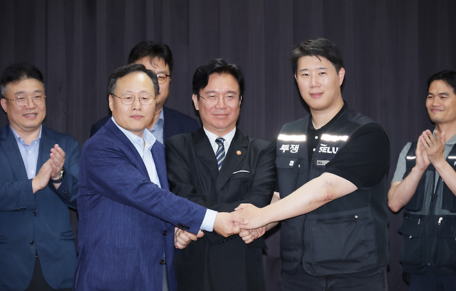 20일 경기도 수원시 장안구 경기고용노동청에서 열린 삼성전자 임금협상을 마친 후 여명구 삼성전자 DS(반도체) 피플팀장과 최승호 삼성그룹 초기업노동조합 삼성전자지부 위원장이 잠정 합의안에 서명한 후 김영환 고용노동부 장관과 손을 맞잡고 있다. 연합뉴스