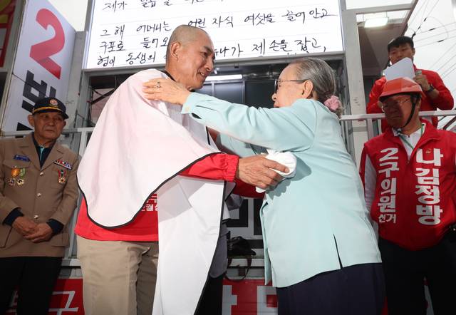 박민식 국민의힘 부산 북갑 보궐선거 후보가 21일 부산 구포시장 쌈지공원에서 열린 출정식에서 어머니의 도움으로 삭발한 뒤 어머니와 포옹하고 있다. 박 후보는 삭발하며 “배신자 한동훈과 단일화하지 않겠다”고 말했다. [연합뉴스]