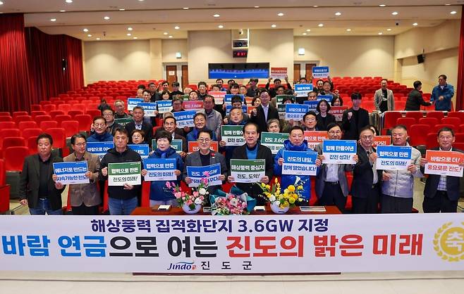 진도군 해상풍력 집적화단지 3.6GW 지정 보고회에 참석한 군민들과 관계자들이 ‘바람연금으로 여는 진도의 밝은 미래’ 현수막 앞에서 기념촬영을 하고 있다.
