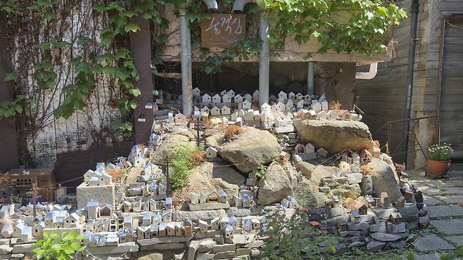 Miniature house-shaped ceramic ornaments placed on top of stones [WOO JI-WON]