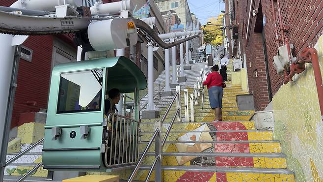 A monorail glides up the "Wish Stairs" in Dakbatgol Mural Village in Seo District. [WOO JI-WON]