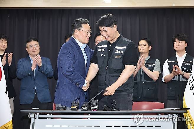잠정 합의안 서명한 삼성전자 노사 (수원=연합뉴스) 홍기원 기자 = 20일 경기도 수원시 장안구 경기고용노동청에서 열린 삼성전자 임금협상을 마친 후 여명구 삼성전자 DS(디바이스솔루션·반도체 사업 담당) 피플팀장과 최승호 삼성그룹 초기업노동조합 삼성전자지부 위원장이 잠정 합의안에 서명한 후 손을 맞잡고 있다. 2026.5.20 [공동취재] xanadu@yna.co.kr