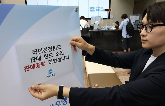 국민참여성장펀드 가입 첫날인 22일 서울 중구 우리은행 본점 영업점에서 한 직원이 한도소진으로 인한 판매종료 안내문을 붙이고 있다. /연합뉴스