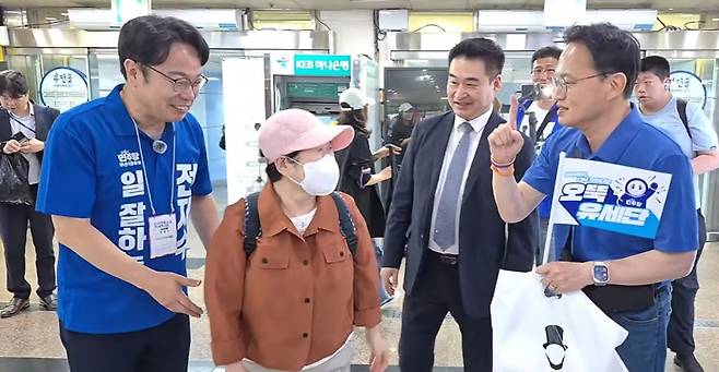 박주민 민주당 의원(오른쪽)이 '오뚝 유세단' 팻말을 들고 이재성 전 부산시당위원장(왼쪽)과 부신 시민에게 전재수 부산시장 후보 지지를 호소하고 있다. 사진 유튜브 '박주민TV' 캡쳐