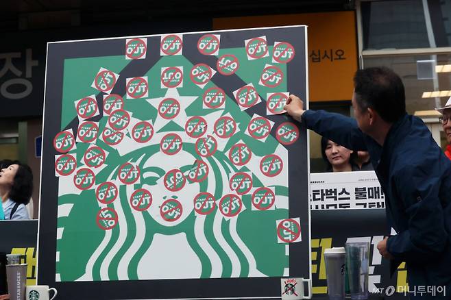 (광주=뉴스1) 조수민 수습기자 = 오월을 사랑하는 모임 등 광주시민단체 들이 21일 오후 광주 서구 광천동 이마트 광주점 앞에서 스타벅스의 '5·18 탱크데이' 마케팅을 규탄하는 기자회견을 열고 스타벅스 OUT 스티커를 붙이고 있다. 2026.5.21/뉴스1  Copyright (C) 뉴스1. All rights reserved. 무단 전재 및 재배포,  AI학습 이용 금지. /사진=(광주=뉴스1) 조수민 수습기자