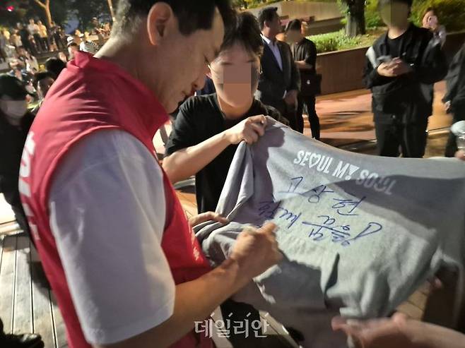 오세훈 국민의힘 서울시장 후보가 23일 송파구 잠실동 석촌호수에서 한 청년의 요청에 서울시 공식 후드티에 사인을 하고 있다. ⓒ데일리안 김주훈 기자