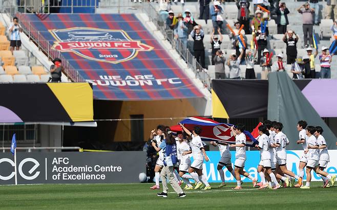 23일 경기 수원종합운동장에서 열린 AWCL 결승전에서 우승한 내고향여자축구단 선수들이  인공기를 펼치고 그라운드를 달리고 있다. 연합뉴스