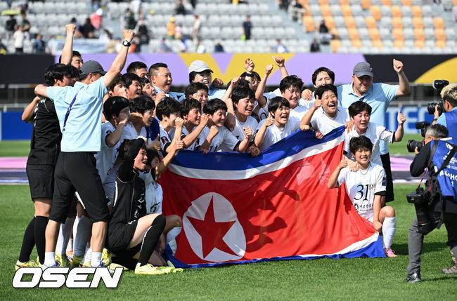 [OSEN=수원, 이대선 기자] 우승컵도, 100만 달러(약 15억 원) 우승 상금도 북한 내고향여자축구단 차지가 됐다. 논란 속 한국에서 열린 결승전에서 내고향은 일본 도쿄 베르디 벨레자를 꺾고 아시아 정상에 올랐다. 경기장 분위기 역시 마지막까지 씁쓸함을 남겼다.내고향은 23일 오후 수원종합운동장에서 열린 2025-2026 아시아축구연맹(AFC) 여자 챔피언스리그(AWCL) 결승전에서 도쿄 베르디를 1-0으로 꺾고 우승을 차지했다. 이날 공식 관중은 2670명이었다.경기 종료 후 내고향여자축구단 선수단이 인공기를 펼치고 기념촬영을 하고 있다. 2026.05.23 /sunday@osen.co.kr