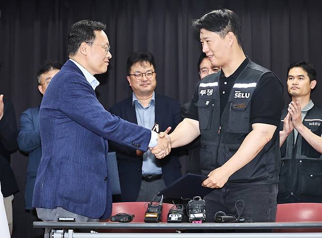 5월20일 경기 수원시 장안구 경기고용노동청에서 열린 삼성전자 임금협상을 마친 후 여명구 삼성전자 DS(디바이스솔루션·반도체 사업 담당) 피플팀장과 최승호 삼성그룹 초기업노동조합 삼성전자지부 위원장이 잠정 합의안에 서명한 후 악수하고 있다. ⓒ공동취재